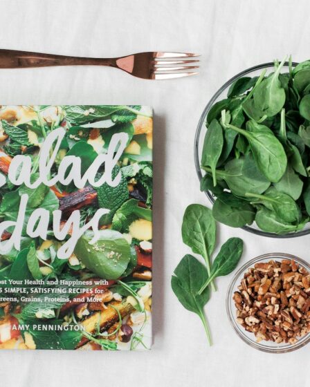 Salad day cookbook beside clear glass bowl with vegetable